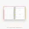 Open wire-bound book with self-assessment worksheets on a white background