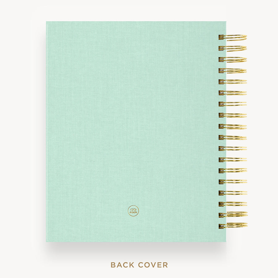 Mint green notebook with gold spiral binding on a white background