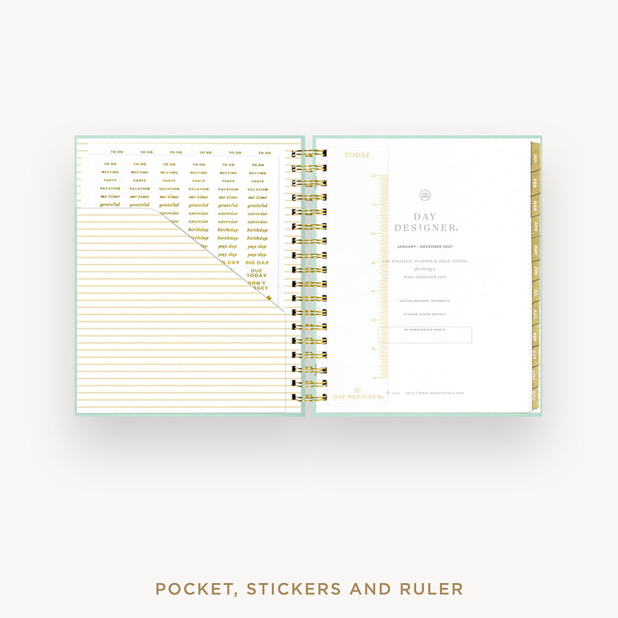 Open planner showing pages with pocket, stickers, and ruler on a white background