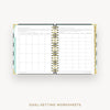 Open wire-bound notebook displaying goal-setting worksheets on a white background.
