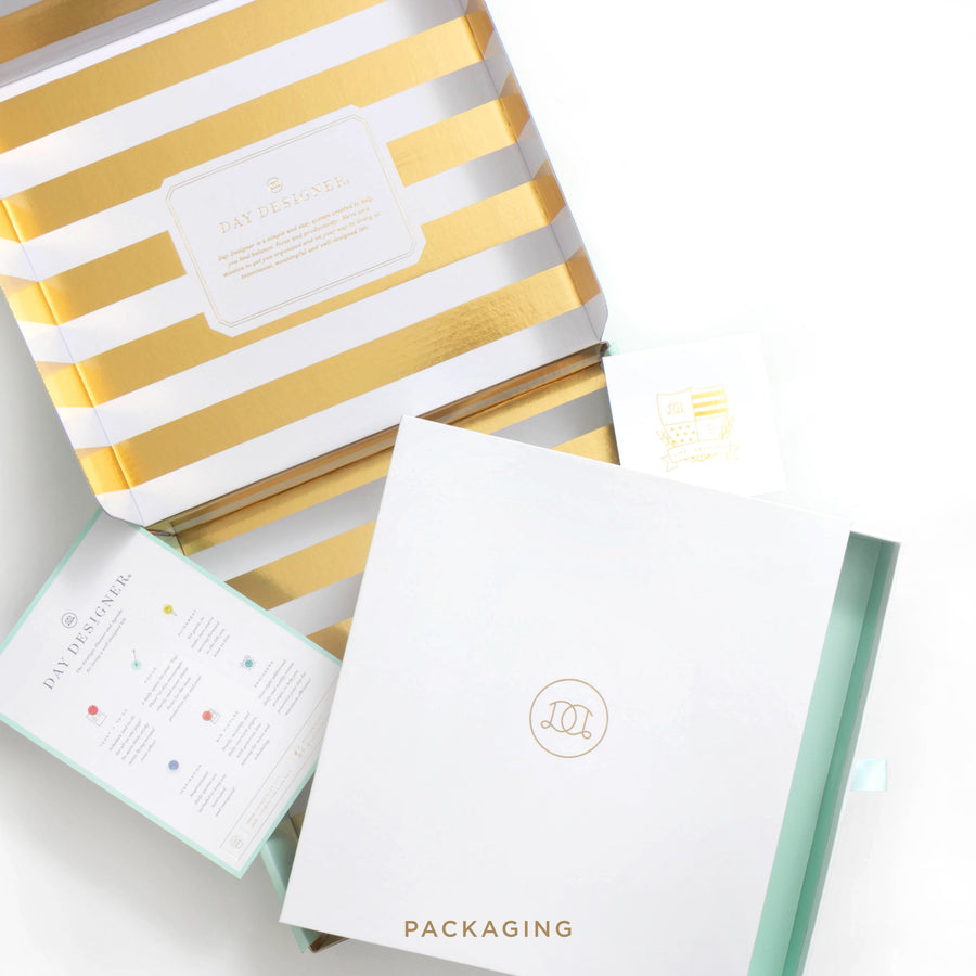 Gold and white striped packaging box with a white card inside on a light gray background