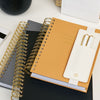 stacked gray, black, and caramel planners, attached pen holder with two pens, notebooks and notepads