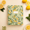 Notebook with lemon pattern on a light beige background with lemons and leaves.