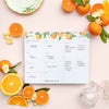 Filled in weekly Menu Planning Pad with grocery list on a pink background. Orange Blossom design.